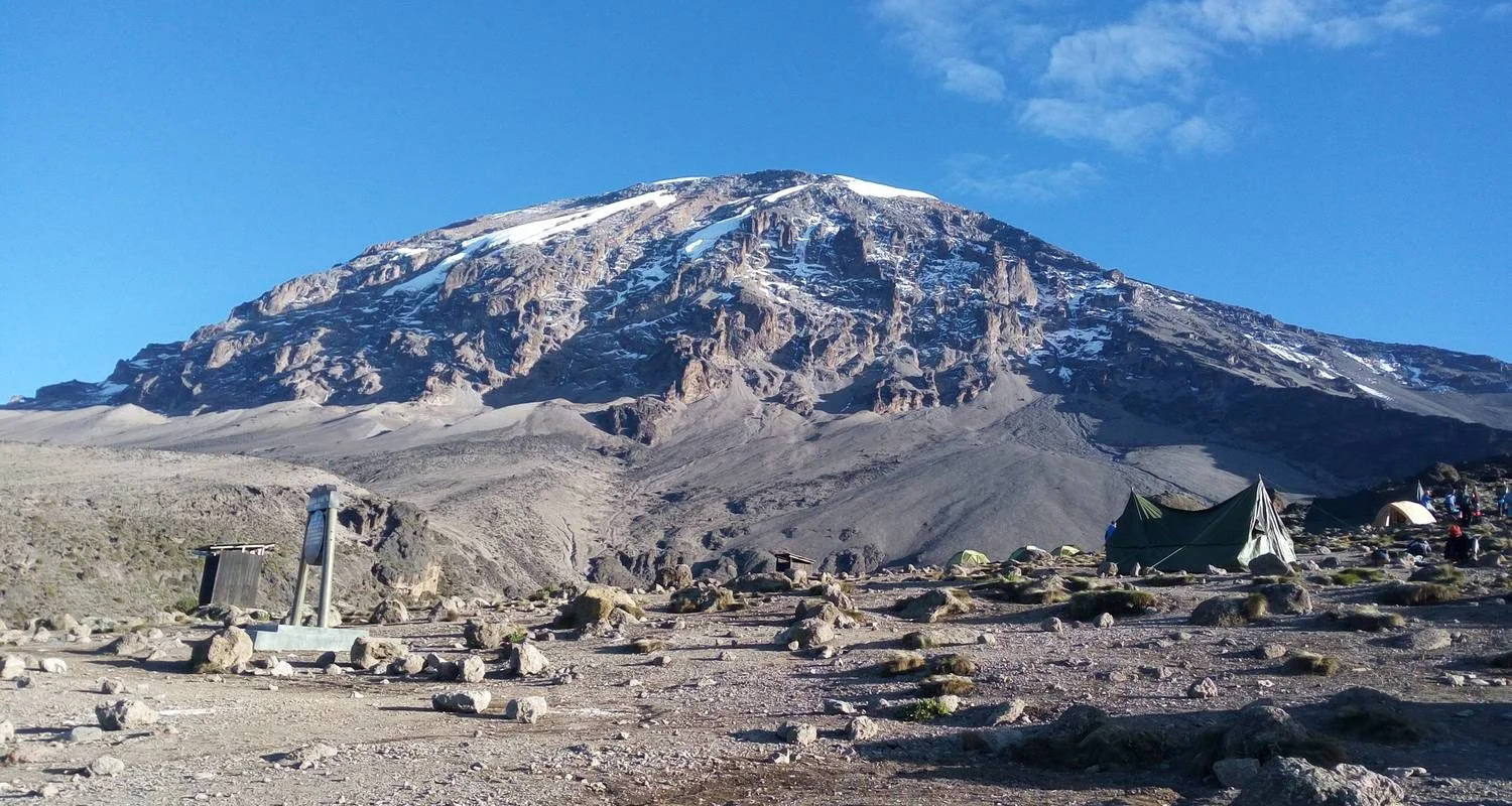 Kilimanjaro climbers at summit celebrating with Bush Lion Tours banner